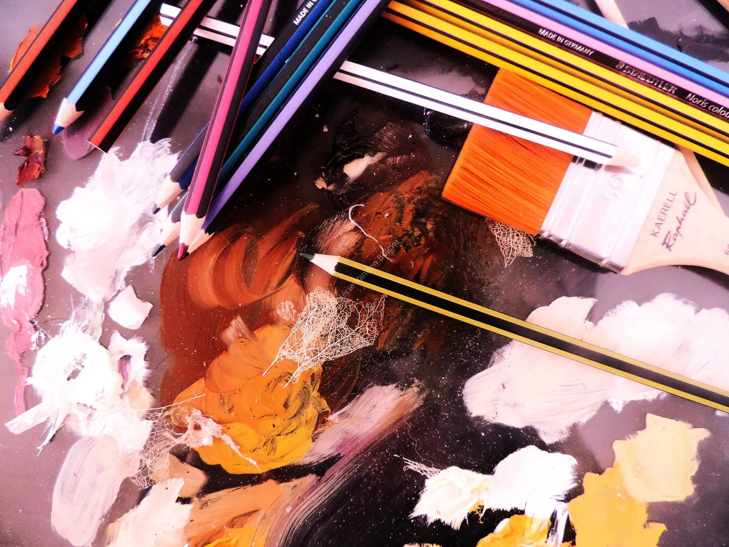 La table de l'atelier : crayons, pinceaux et couleurs en cours de travail